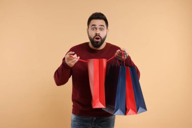 Bej arka planda bir sürü kese kağıdıyla şok olmuş bir adam.