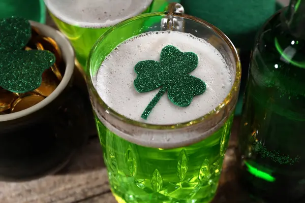 St. Patrick's day party. Green beer, leprechaun pot of gold and decorative clover leaves on wooden table, closeup