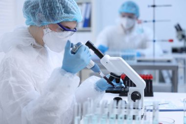 Laboratuvarda mikroskopla çalışırken cam parçasına kan damlatan bir bilim adamı.