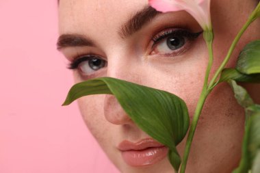 Sahte çilleri ve pembe arka planda çiçekleri olan güzel kadın, yakın plan.