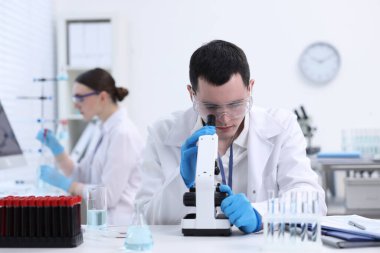 Laboratuvarda mikroskopla çalışan bir bilim adamı. Tıbbi araştırma