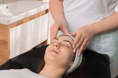 Kozmetik uzmanı klinikteki müşteriye yüz masajı yapıyor.