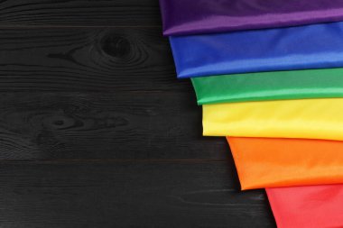 Siyah ahşap arka planda gökkuşağı LGBT bayrağı, yakın plan. Metin için boşluk
