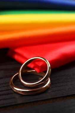 Gökkuşağı LGBT bayrağı ve siyah ahşap arka planda alyanslar