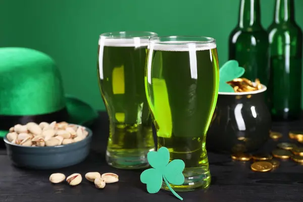 St. Patrick\'s day party. Green beer, leprechaun hat, pot of gold, pistachios and decorative clover leaf on wooden table