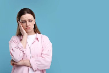 Açık mavi arkaplanda üzgün kadın portresi, metin için boşluk