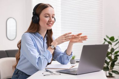 E-öğrenme. Beyaz masa içinde online ders sırasında dizüstü bilgisayar kullanan genç bir kadın.