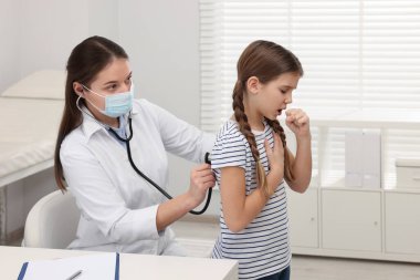 Hastanede öksüren kızı muayene eden doktor. Soğuk belirtileri
