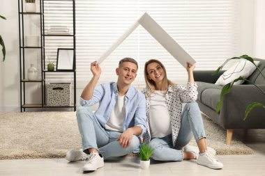 Genç aile konutları. Hamile bir kadın ve kocası karton çatının altında oturuyorlar.