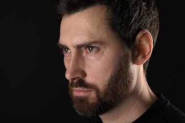 Kem göz. Siyah arka planda korkunç gözleri olan adam, yakın plan.