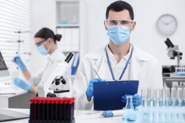 İçerideki masada laboratuvar test formu üzerinde çalışan bir bilim adamı.