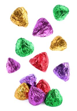 Beyaz arka plana düşen parlak ambalajlı lezzetli şekerler.