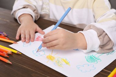 Ahşap masada kalemle çizen küçük çocuk, yakın plan. Çocuk sanatı