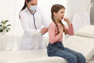 Hastanede öksüren kızı muayene eden doktor. Soğuk belirtileri