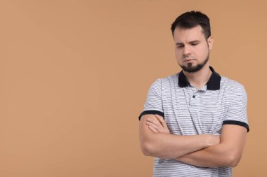 Bej arka planda çapraz kollu üzgün adamın portresi, metin için boşluk