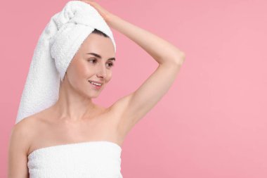 Güzel bir kadın pembe arka planda pürüzsüz ciltli koltukaltını gösteriyor, mesaj için yer var.