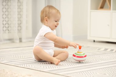 Çocuk oyuncakları. Evdeki halının üstünde dönen şirin bir çocuk.