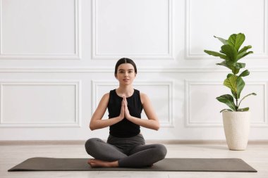 Yoga stüdyosunda minder üzerinde meditasyon yapan güzel kız.