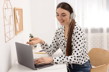 E-öğrenme. İçerideki masada online ders sırasında dizüstü bilgisayar kullanan genç bir kadın.