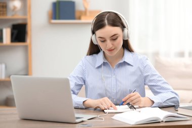 E-öğrenme. İçerideki masada ders alan bir kadın.