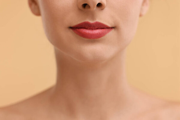 Woman with beautiful lips on beige background, closeup