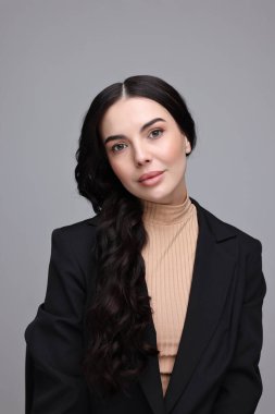 Gri arka planda siyah ceketli güzel kadın.