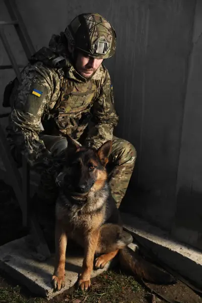 Ukrainian soldier with German shepherd dog sitting outdoors