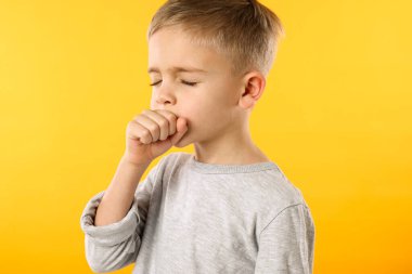 Hasta çocuk sarı arka planda öksürüyor. Soğuk belirtileri