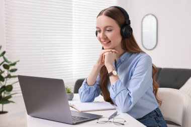 E-öğrenme. Beyaz masa içinde online ders sırasında dizüstü bilgisayar kullanan genç bir kadın.
