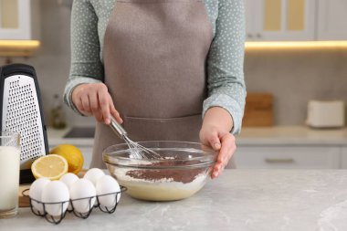 Çikolata hamuru yapan kadın gri mermer masada çırpıcıyla, yakın plan.