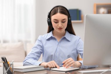 E-öğrenme. İçerideki masada ders sırasında not alan genç bir kadın.