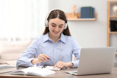 E-öğrenme. İçerideki masada ders alan bir kadın.