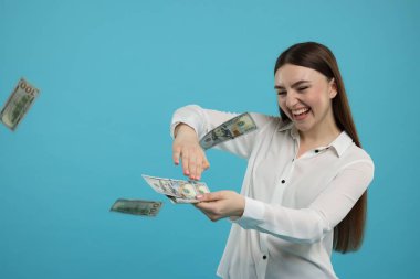 Mutlu kadın açık mavi arka plana para atıyor