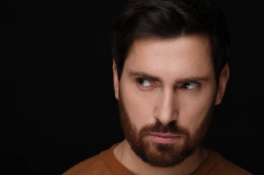 Kem göz. Siyah arkaplanda korkunç gözleri olan adam, yakın plan ve metin için boşluk