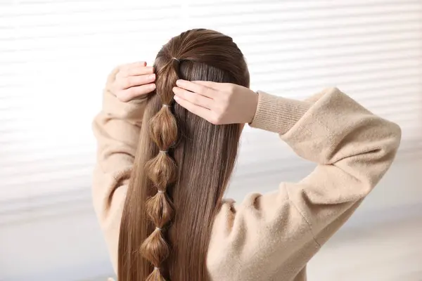 Woman with braided hair indoors, back view