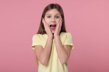 Pembe arka planda şaşırmış bir kızın portresi