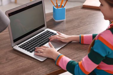E-öğrenme. İçerideki masada çevrimiçi ders sırasında dizüstü bilgisayar kullanan kız.