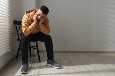 Pencerenin yanındaki sandalyede oturan üzgün adam. Metin için boşluk