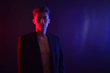 Karanlık arka planda, neon ışıklı seksi genç adam. Metin için boşluk