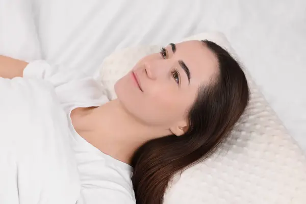 Woman lying on orthopedic pillow in bed