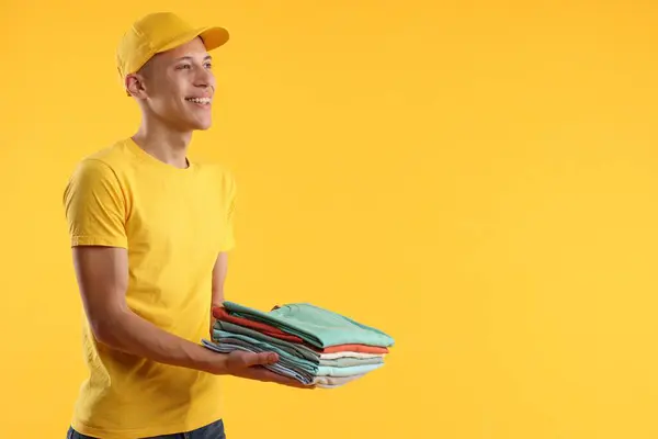 Kuru Temizleme Portakal Rengi Arka Planda Katlanmış Giysiler Taşıyan Mutlu — Stok fotoğraf