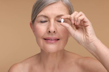 Bej arka planda vitamin hapı olan güzel bir kadın.