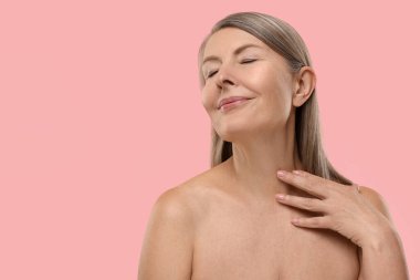 Pembe arka planda sağlıklı cildi olan güzel bir kadın, mesaj için yer var.