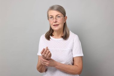 Artrit belirtileri. Gri arka planda bilek ağrısı çeken bir kadın.