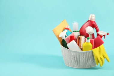 Açık mavi arkaplanda sepette farklı temizlik ürünleri, metin için boşluk
