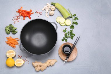 Wok, yemek çubukları ve gri masada farklı ürünler, düz yatak. Metin için boşluk