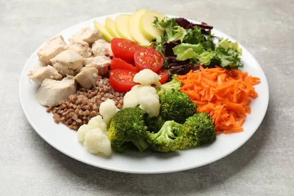 Dengeli beslenme ve sağlıklı yiyecekler. Gri masadaki farklı lezzetli ürünlerin olduğu tabaklar, yakın plan.