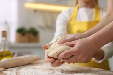 Ekmek yapıyorum. Anne ve kızı mutfaktaki ahşap masada hamur yoğuruyorlar.