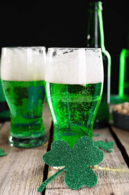 St. Patrick 'in gündüz partisi. Yeşil bira ve ahşap masa üzerindeki dekoratif yoncalar.