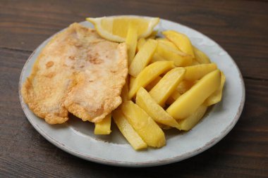 Lezzetli balık ve patates kızartması ahşap masada, yakın plan.